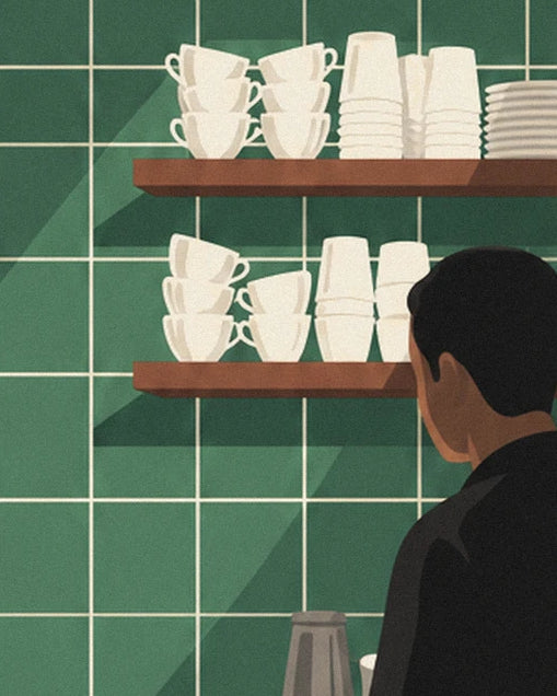 The cups and glasses stacked on 2 wooden shelves, with the barista seen from behind in front of the green tiled wall