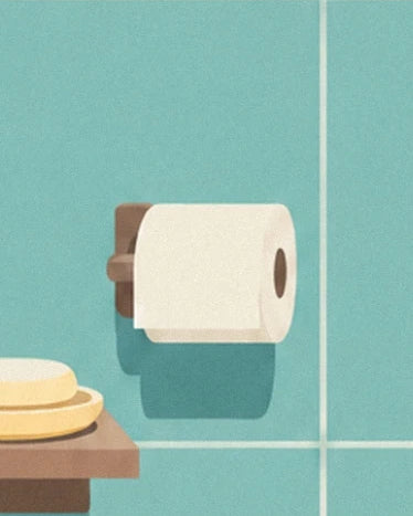 Eine Toilettenpapierrolle auf ihrem braunen Halter, neben gelben Seifen