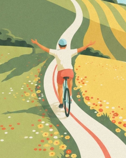 The cyclist seen from behind with arms outstretched on a winding road lined with flowers