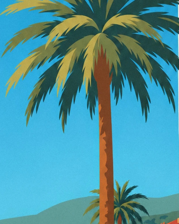 A tall palm tree with green and golden fronds against the blue sky of Nice