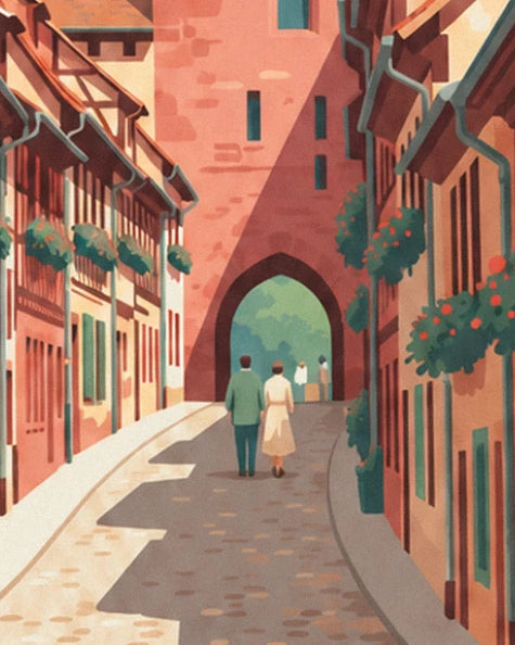 A couple walking towards the fortified pink sandstone gateway along a cobbled lane lined with flower-covered houses